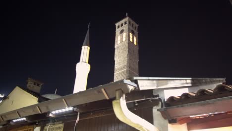 detalle arquitectónico de la antigua torre del reloj y el minarete de la mezquita de gazi husrev beg por la noche en sarajevo, bosnia y herzegovina
