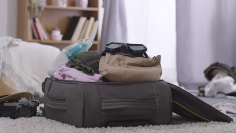 open suitcase in bedroom at home being packed for summer holiday