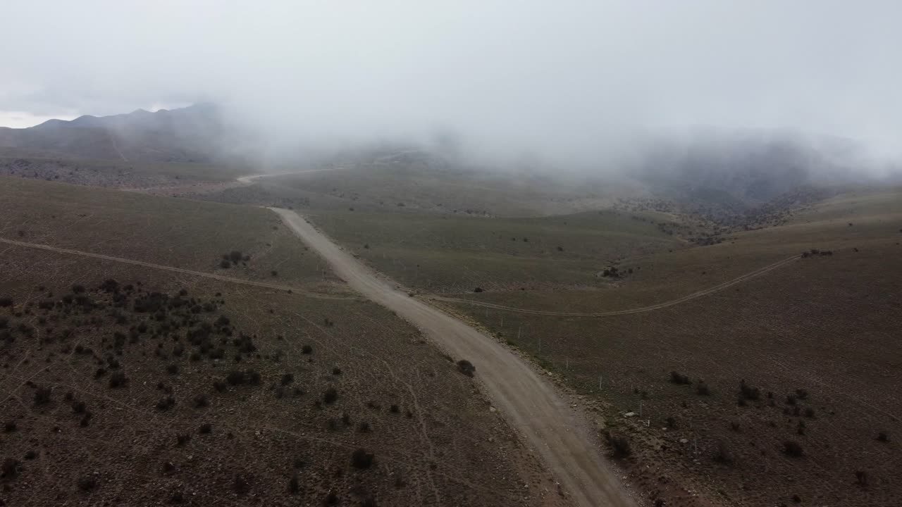 la antena de nubes bajas sigue un camino de grava en la meseta montañosa niebla, los andes