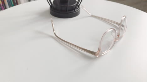 modern eyeglasses in light colour lie on a white table, bright glasses frame, slow motion footage