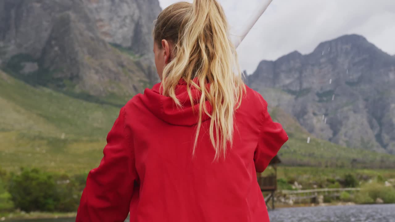 Caucasian woman having a good time on a trip to the mountains, kayaking on a lake, holding a paddle