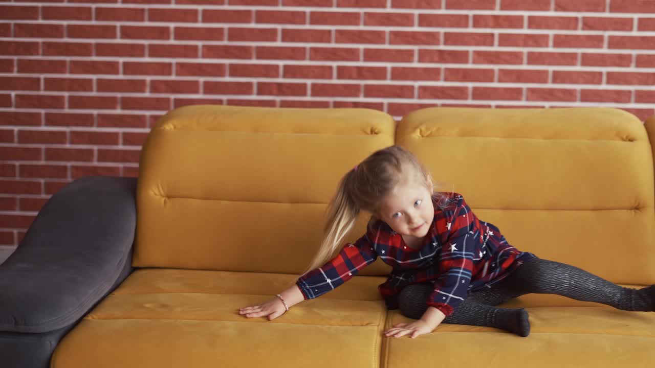 niña haciendo una voltereta o un rollo hacia adelante en el sofá en casa