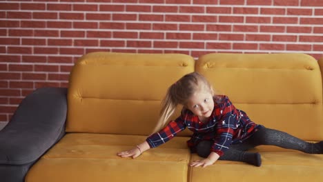 niña haciendo una voltereta o un rollo hacia adelante en el sofá en casa