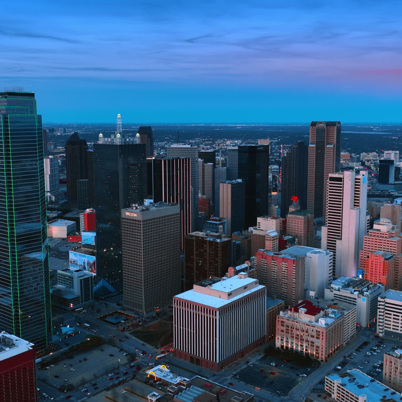 Sorvolo sopra il centro di Dallas, Texas, USA al tramonto. La città accende le luci al crepuscolo. Prospettiva aerea.