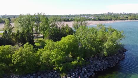 Umlaufende-Drohnenaufnahme-Eines-Punktes-Am-Lake-Ontario-Mit-Einem-Strand-Von-Toronto-Und-Booten-Im-Hintergrund