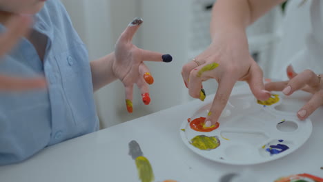 los niños dibujan sus dedos en papel usando pinturas