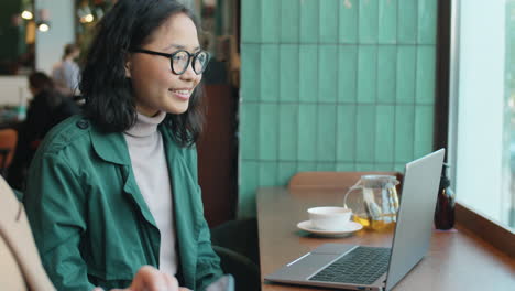 Videoanruf-Einer-Asiatischen-Frau-Auf-Einem-Laptop-Im-Café