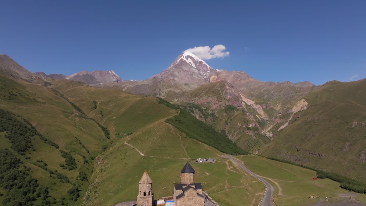el retroceso aéreo revela la famosa iglesia de la trinidad de gergeti, la montaña kazbek en verano