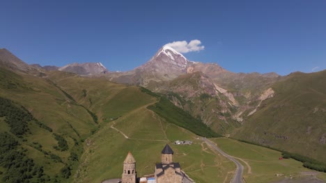 el retroceso aéreo revela la famosa iglesia de la trinidad de gergeti, la montaña kazbek en verano