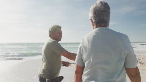 vista de atrás de una feliz pareja de ancianos hispanos caminando con bicicletas en la playa al atardecer