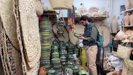 a tourist man is selecting handmade crafts made by clay mud colorful enamel container pot to make persian local food cuisine culinary recipe for family dining table stew frying pan for lovely couple