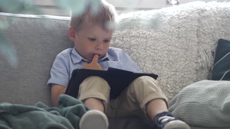 Portrait-Of-Cute-Caucasian-Boy-In-Sofa-Using-Tablet,-Static-Shot