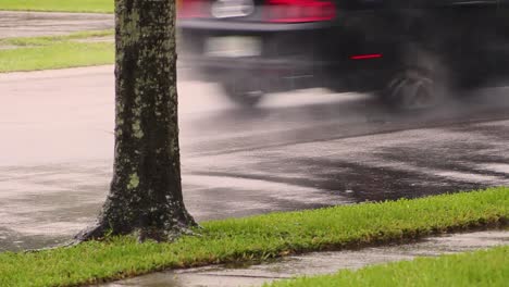 car drives down wet street while raining in slow motion