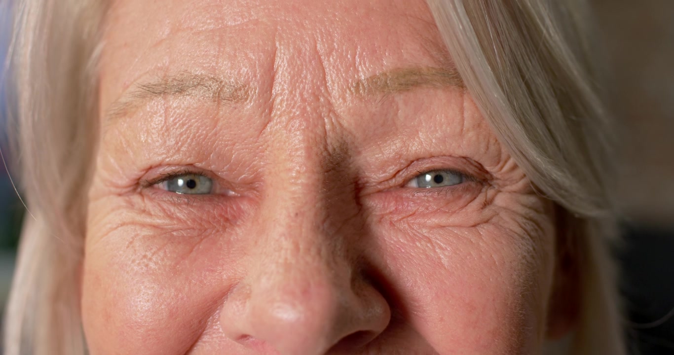 Senior woman reacting to soft light in studio, squinting, blinking, smiling, showing forehead lines