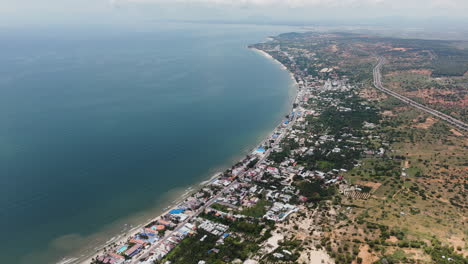 Vuelo-Aéreo-En-Círculos-Sobre-La-Playa-De-Mui-Ne,-Phan-Thiet-En-La-Distancia,-Vietnam