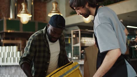 a market donor worker helps a food delivery man place an order, after which they high-five in approval. teamwork of the restaurant and food delivery