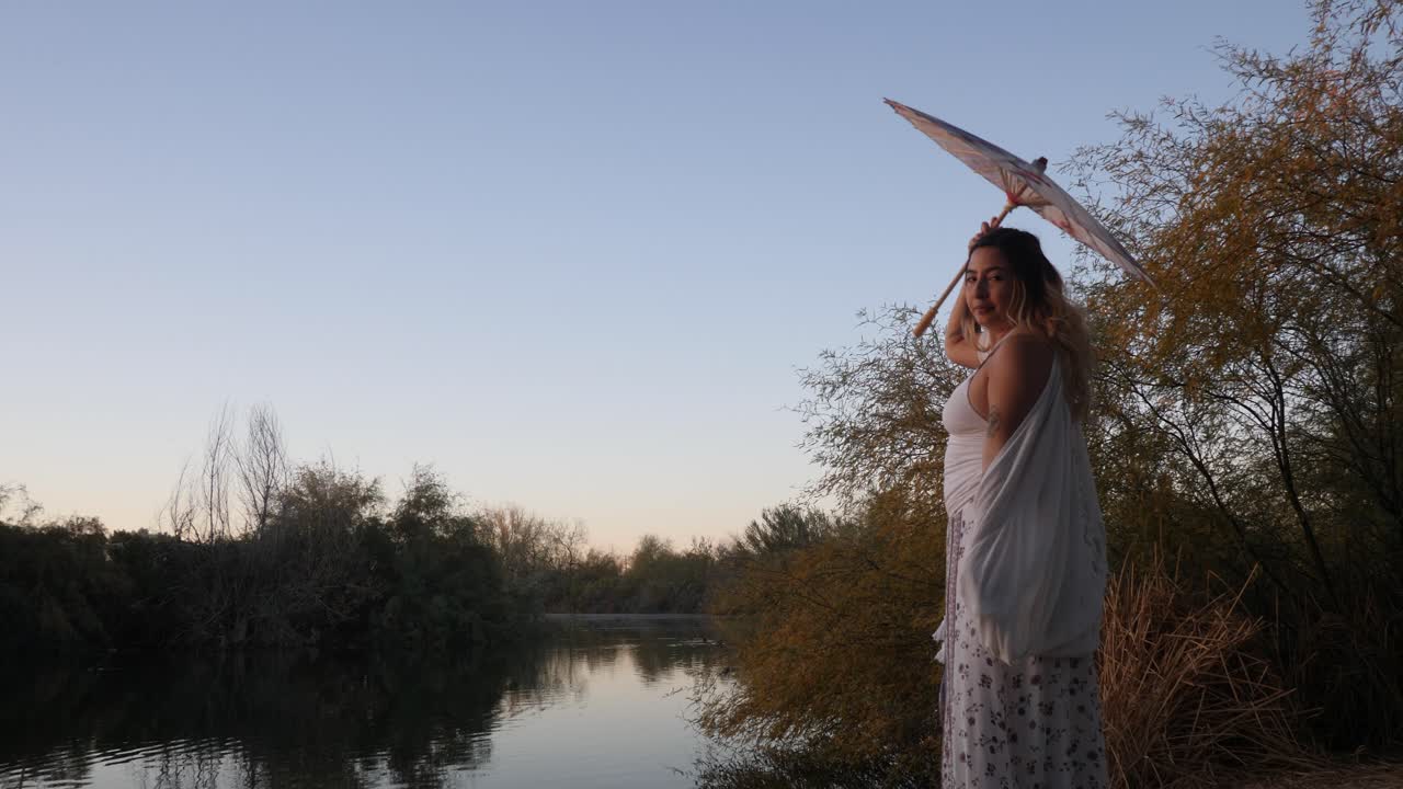 movimiento lento de una hermosa chica girando un paraguas al lado de un río.