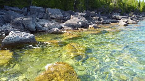 drone shot flying low across the rocky coastline and crystal clear waters of georgian bay, ontario, canada