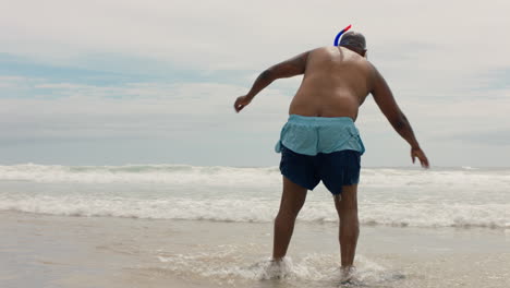 Gracioso-Hombre-Afroamericano-En-La-Playa-Mirando-Las-Olas-Del-Océano-Preparándose-Para-Nadar-Disfrutando-De-Las-Vacaciones-De-Verano-Usando-Snorkel-Y-Aletas-4k