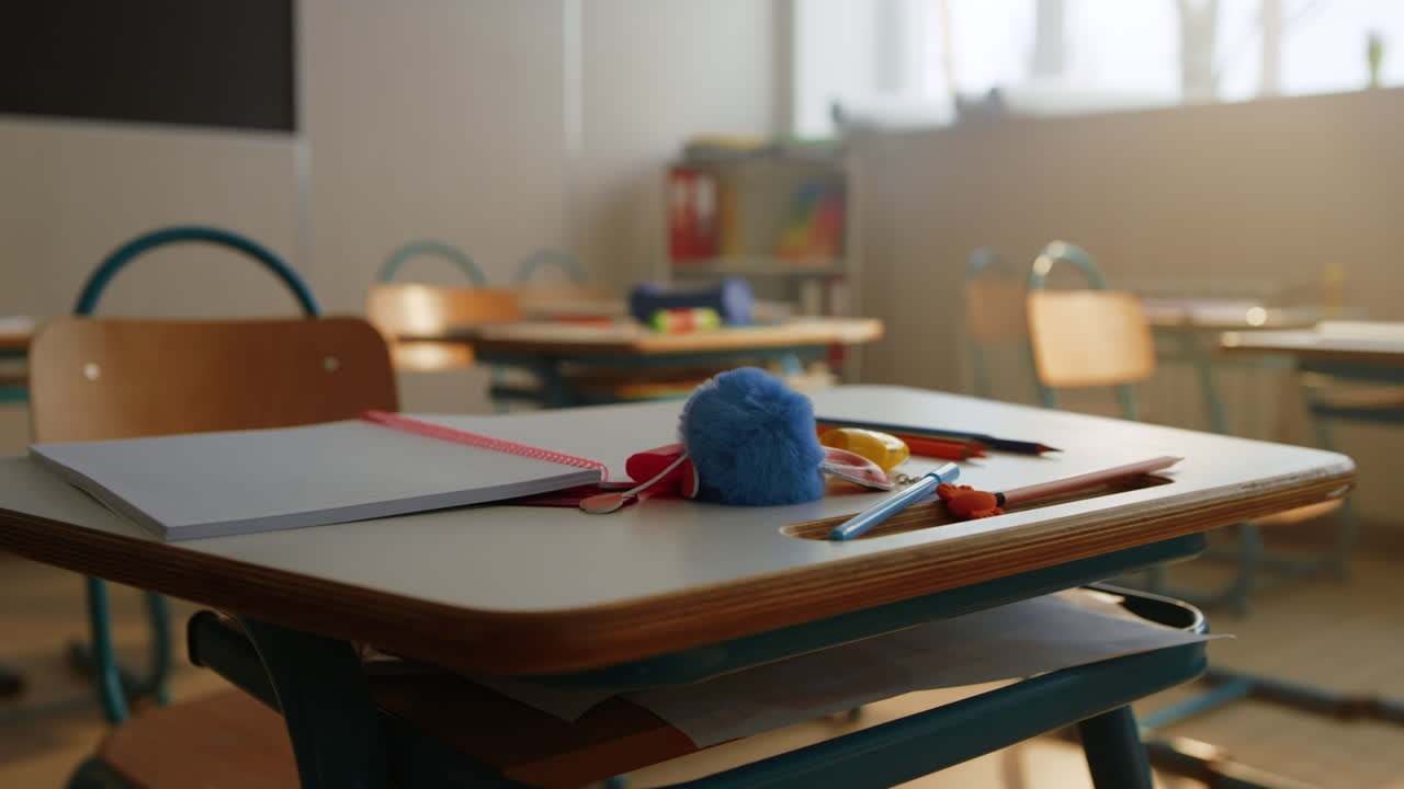 Notebook and pencils lying on desk in classroom. Table with school supplies