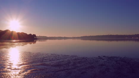 Rayos-De-Sol-Brillantes-Del-Amanecer-Brillando-En-Una-Playa-Tranquila-En-Auckland,-Nueva-Zelanda