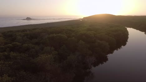 lone rock off the coast during sunset