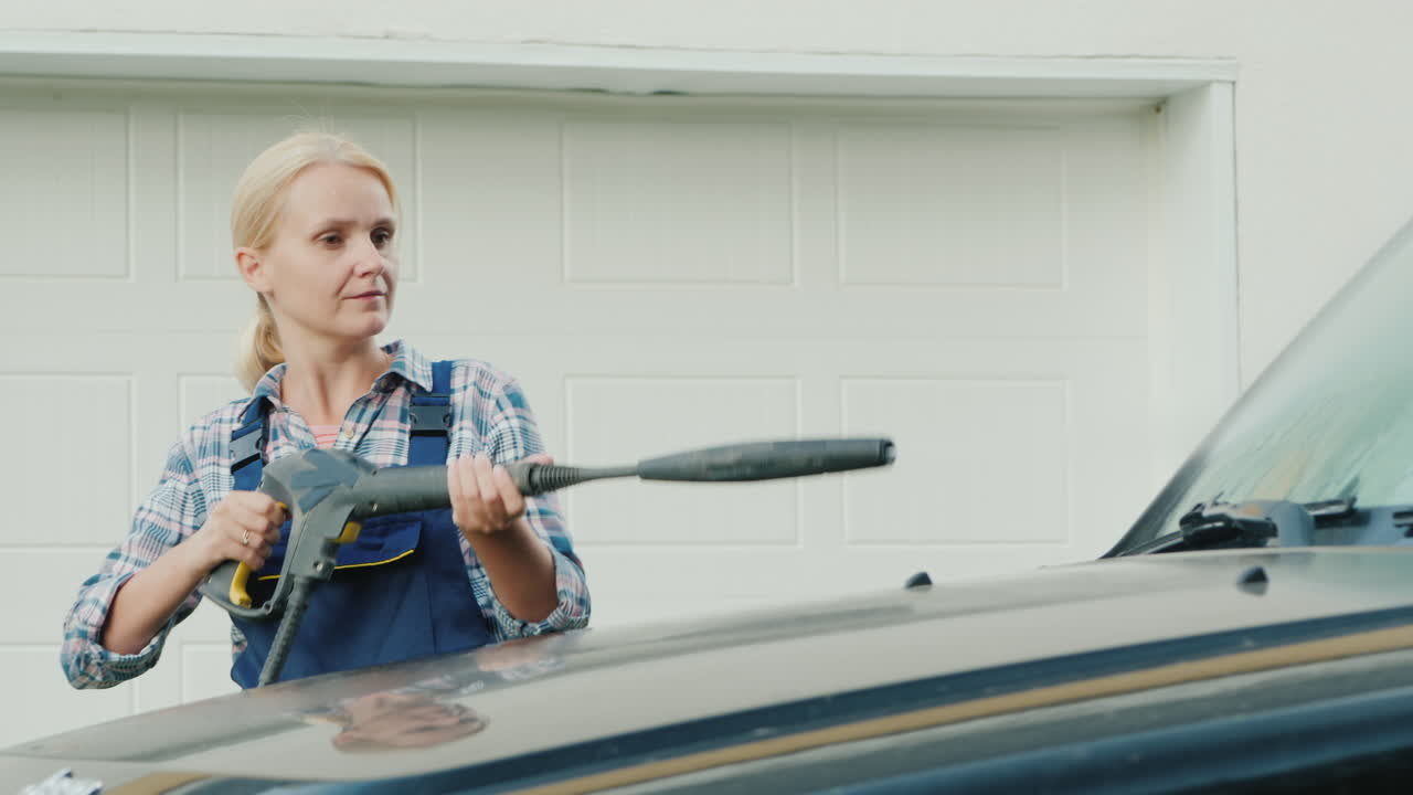 retrato de una mujer activa lavando su auto cerca del garaje