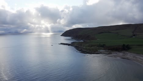 beautiful aerial shot on the coast of scotland with green hills and sun