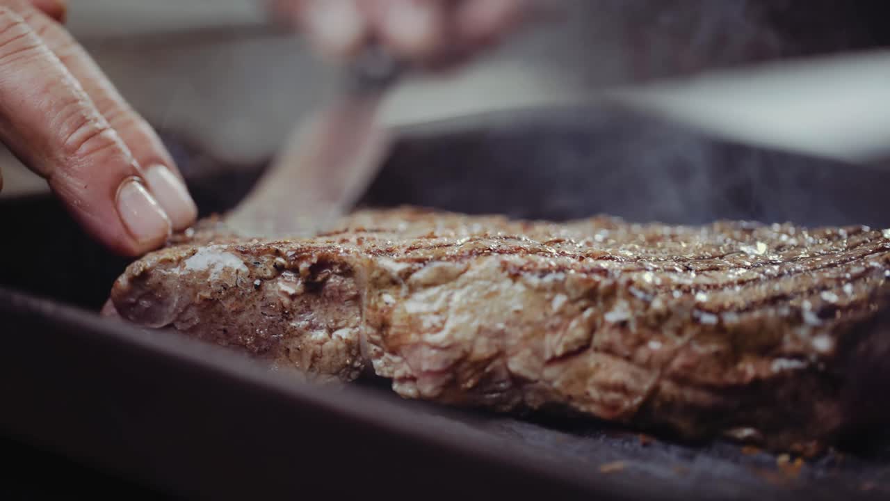 CLOSE UP : Steak being flipped and cooked on a grill pan