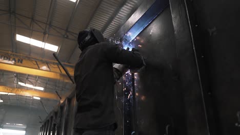 slow motion of indian professional welder technician working with mask for protection from fire sparks in a metal iron steel truck trailer production, asia manpower