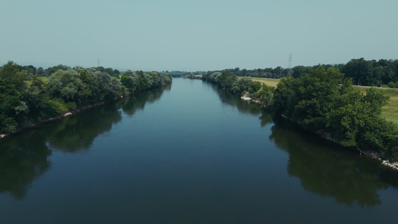 aerial view of still blue river reflecting trees on both banks under clear sky