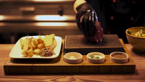 cook preparing raw piece of meat on hot cooking stone, cinematic shot