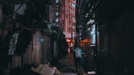 a man walking away in a creepy, dirty little street during the night in a city