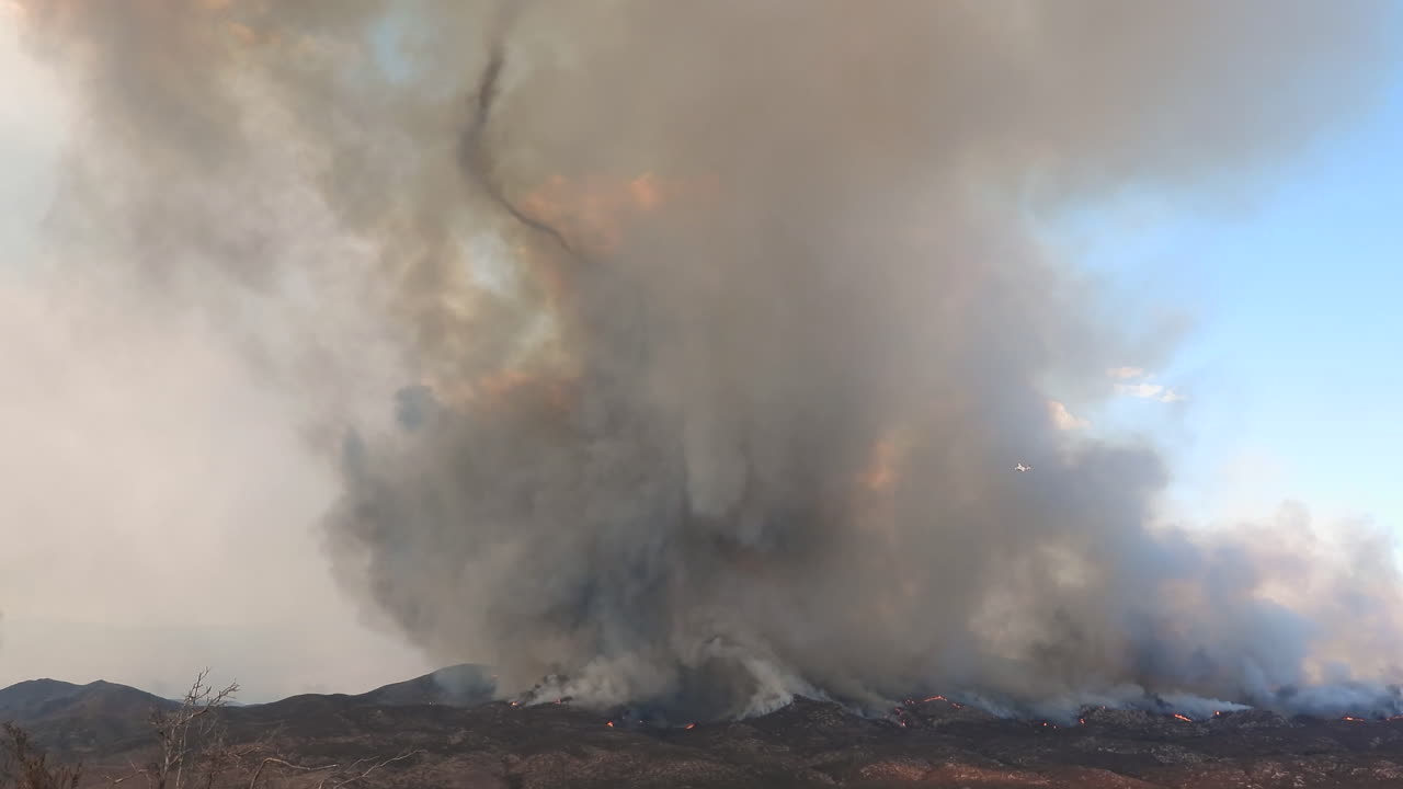 humo negro y gris que sale de un incendio forestal que arde en una montaña