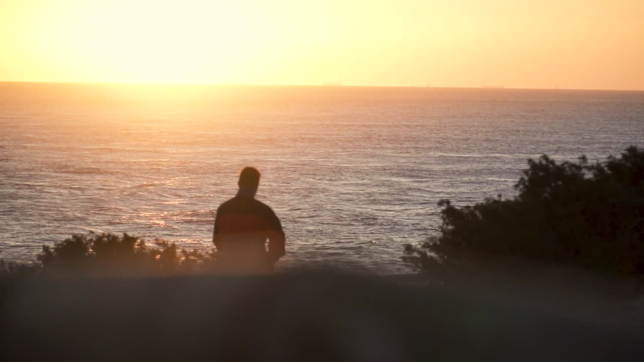toma en cámara lenta del hombre caminando hacia el mar al atardecer, cádiz, españa