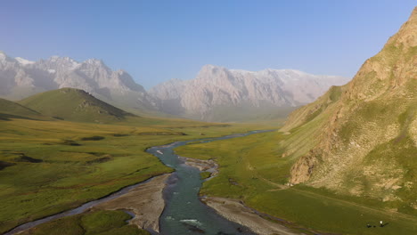 epische roterende drone-opname vanuit de lucht van een kleine rivier naast een berg nabij het kel-suu-meer in kirgizië