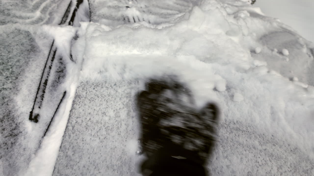 Man with brown leather gloves uncovering the car front window from frozen snow in winter