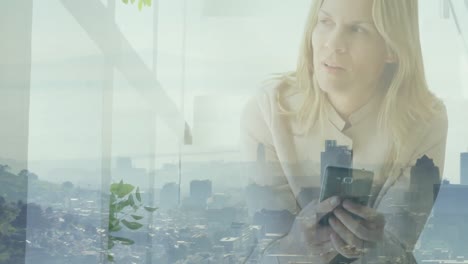 Animation-of-cityscape-over-caucasian-businesswoman-using-smartphone