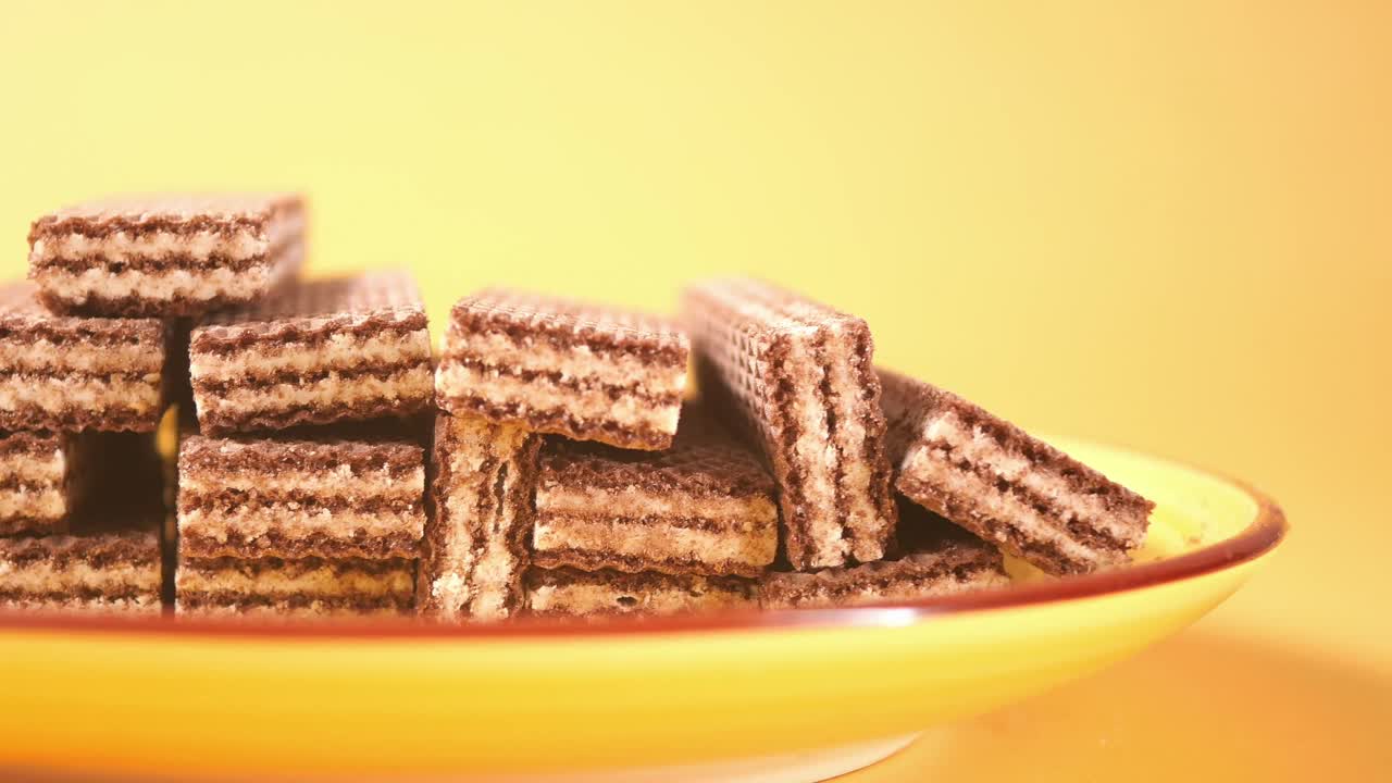 Deliziosi biscotti wafer al cioccolato impilati su un piatto giallo