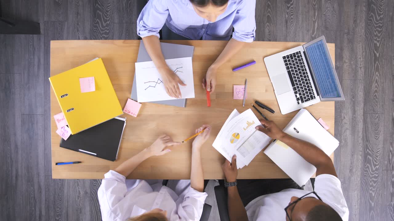 vista superior de la mesa de madera con teléfonos móviles, portátiles, tabletas y documentos con diagramas