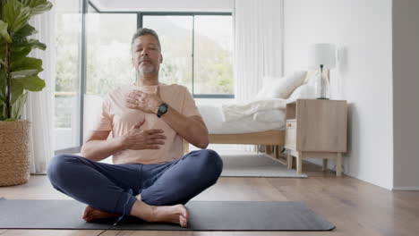 Senior-biracial-man-practicing-yoga-meditation-at-home