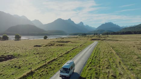 aerial view of tourist campervan on road trip through remote rural countryside and mountainous landscape in glenorchy, south island of new zealand aotearoa