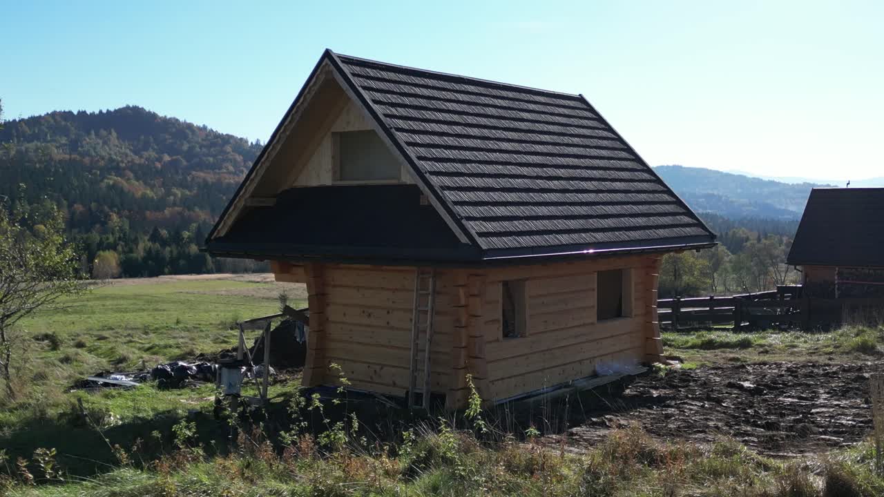 Log Cabin Under Construction in Mountainous Landscape