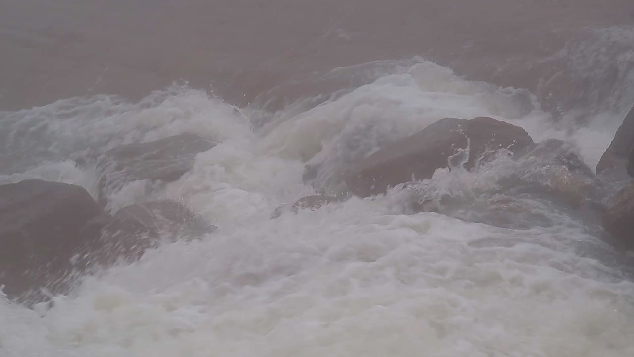 Close up of fast flowing glacier river in remote, stony and foggy environment