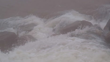 close up of fast flowing glacier river in remote, stony and foggy environment