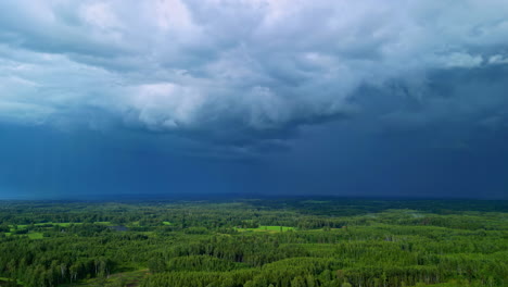 dark rain storm clouds flowing above woodland landscape, aerial drone view