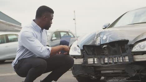 ajustador de pérdidas de seguros tomando una foto con una tableta digital de los daños al coche de un accidente automovilístico
