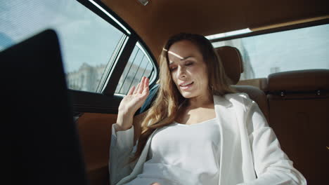 Portrait-of-friendly-business-woman-talking-on-video-call-in-business-car.