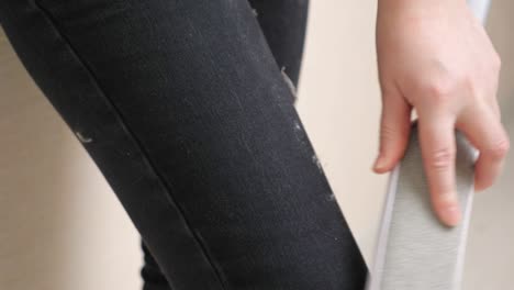 woman cleans pants with electrostatic hair removal brush