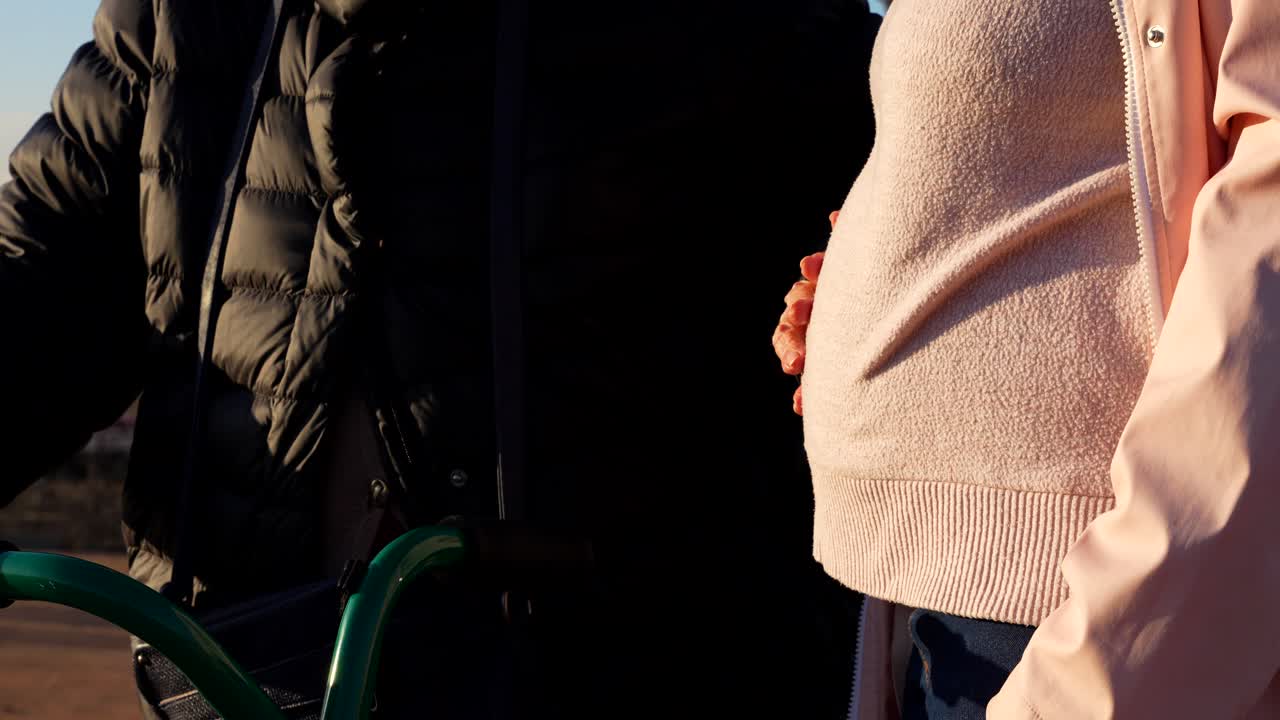 Old wrinkled hand gently touching baby bump, symbolizing family bond and new life